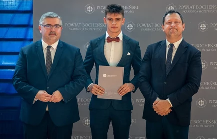 uczeń stojący ze starostą i wicestarostą