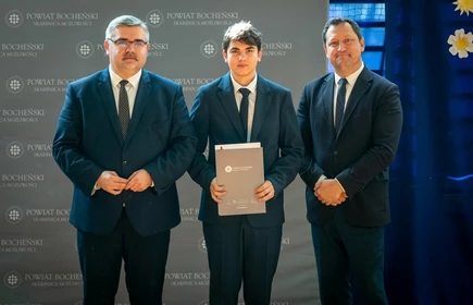uczeń stojący ze starostą i wicestarostą