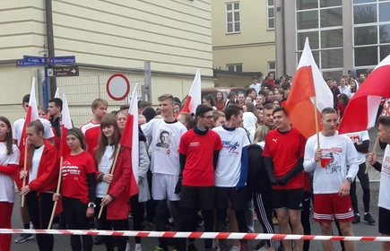 Grupowe zdjęcie na uczestników biegu, osoby wyposażone w polskie flagi