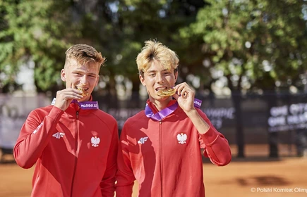 uczniowie w dresach sportowych stojący z medalalmi