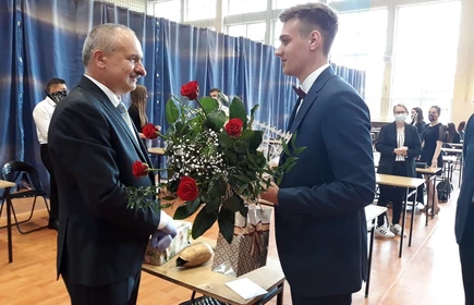 Uczeń wręczający kwiaty nauczycielowi 