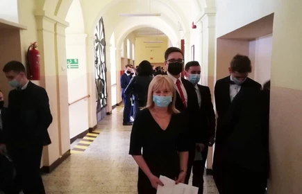 Członek komisji maturalnej oraz maturzyści na korytarzu