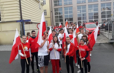 Grupowe zdjęcie na uczestników biegu, osoby wyposażone w polskie flagi