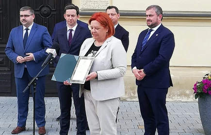 Osoby przemawiają przed drzwiami 1LO