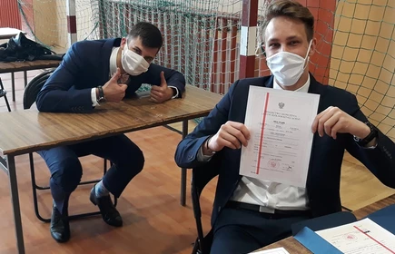 Na zdjęciu uczniowie, jeden trzyma świadectwo