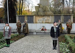 Na zdjęciu osoby biorące udział w obchodach na tle pomnika