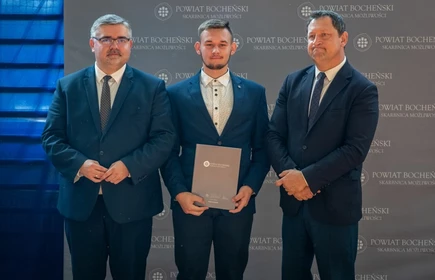 uczeń stojący ze starostą i wicestarostą