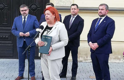 Osoby przemawiają przed drzwiami 1LO