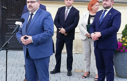 Osoby przemawiają przed drzwiami 1LO