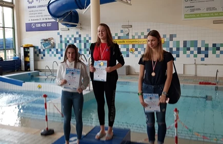 Na zdjęciu trzy uczennice na podium wraz z dyplomami i medalami