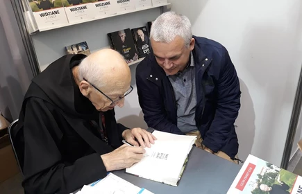 Na zdjęciu autor podpisujący książkę 