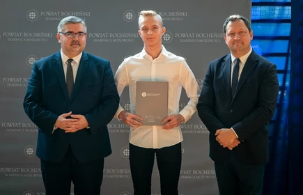 uczeń stojący ze starostą i wicestarostą