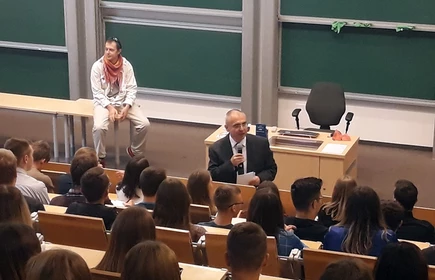Na zdjęciu uczniowie zasiadający na sali wykładowej oraz wykładowca 