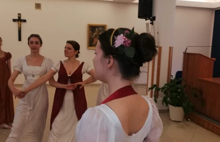 Na zdjęciu kobiety tańczący  w strojach z epoki