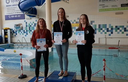 Na zdjęciu trzy uczennice na podium wraz z dyplomami i medalami