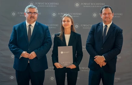 uczeń stojący ze starostą i wicestarostą