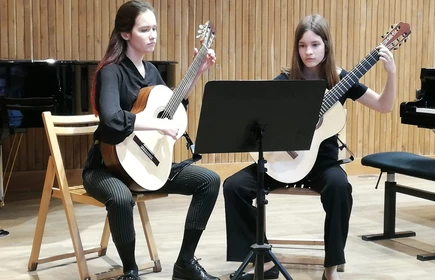 Na zdjęciu dwie kobiety grające na gitarach akustycznych 