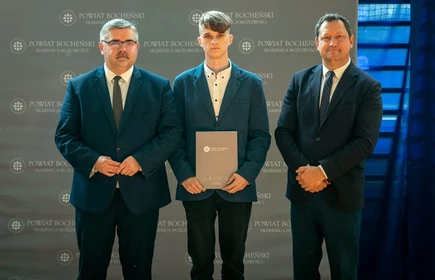 uczeń stojący ze starostą i wicestarostą