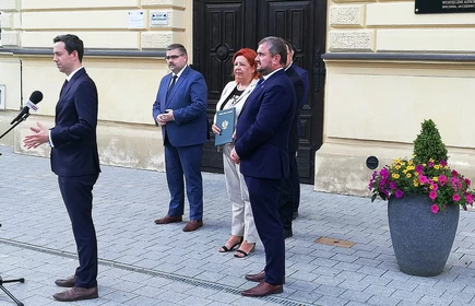Osoby przemawiają przed drzwiami 1LO