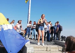 Grupowe zdjęcie uczestników podczas zwiedzania Lwowa na tle flagi Ukrainy. 