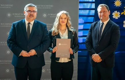 uczeń stojący ze starostą i wicestarostą