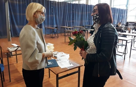 Kobieta wręczająca kwiaty nauczycielce 
