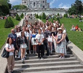 grupa uczniów z nauczycielami stojąca na schodach