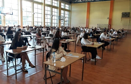 MZdjęcie maturzystów siedzących w przy szkolnych ławkach na sali gimnastycznej atura 2021 8