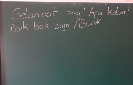 Na zdjęciu tablica szkolna, na której znajdują się indonezyjskie napisy