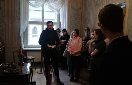 Grupa uczniów w muzeum słuchająca przewodnika