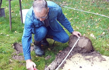 Na zdjęciu specjalista z kawałkiem wykopanej ziemi dokonujący pomiaru 