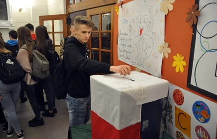 Na zdjęciu uczeń wrzucający kartę wyborczą do urny wyborczej