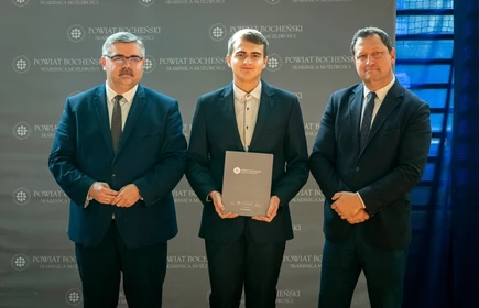 uczeń stojący ze starostą i wicestarostą