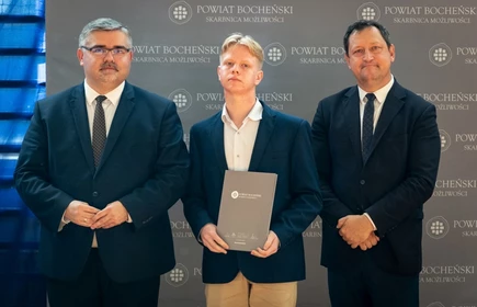 uczeń stojący ze starostą i wicestarostą