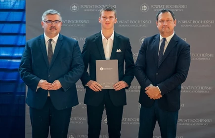 uczeń stojący ze starostą i wicestarostą