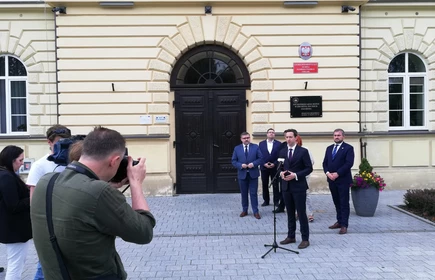 Osoby przemawiają przed drzwiami 1LO