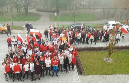Grupowe zdjęcie na uczestników biegu, osoby wyposażone w polskie flagi