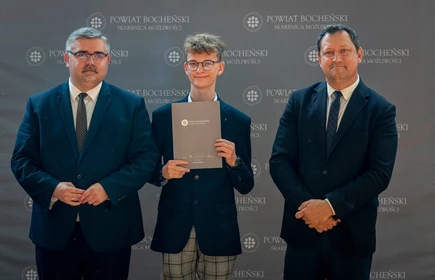 uczeń stojący ze starostą i wicestarostą