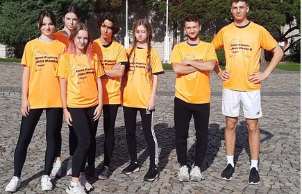 Uczniowie pozują do zdjęcia grupowego w pomarańczowych koszulkach