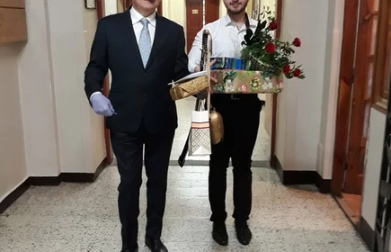 Nauczyciel z prezentami, obok uczeń z kwiatami