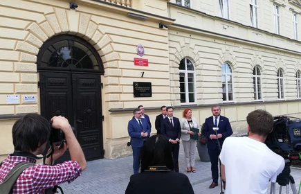 Osoby przemawiają przed drzwiami 1LO