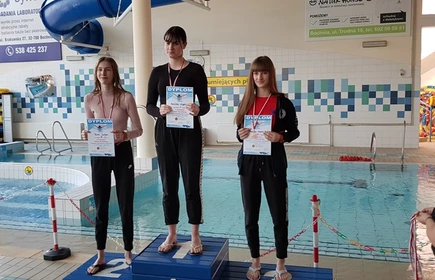 Na zdjęciu trzy uczennice na podium wraz z dyplomami i medalami