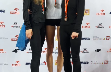 Na zdjęciu trzy kobiety, wszystkie  stojące na podium