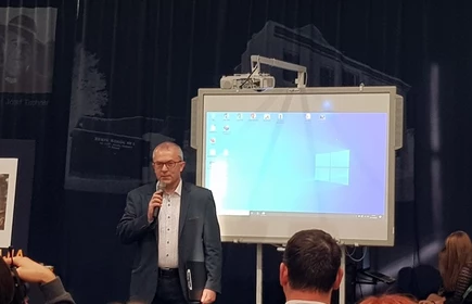 Na zdjęciu mężczyzna przemawiający doi mikrofonu 