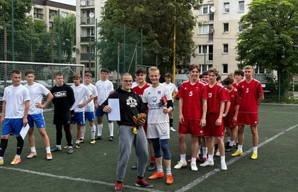 uczniowie stojący na boisku piłki nożnej z dyplomem