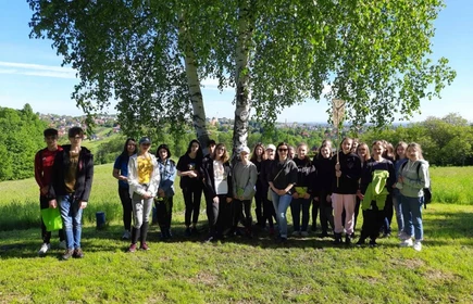 Grupowe zdjęcie uczni&oacute;w na łące pod drzewem 