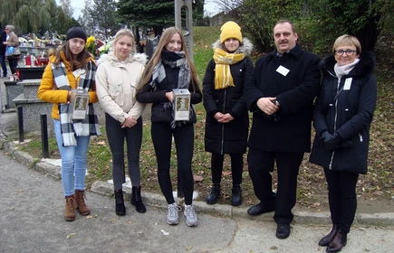 Grupa osób z puszkami podczas kwesty na cmentarzu 