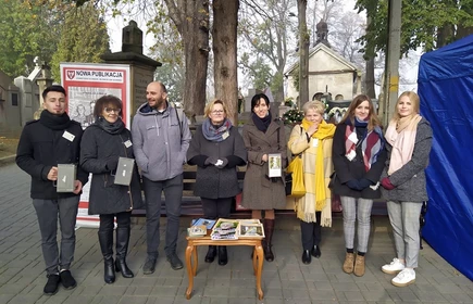Grupa osób z puszkami podczas kwesty na cmentarzu 