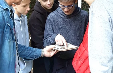 Na zdjęciu uczniowie dokonują analizy barwy wykopanej ziemi 