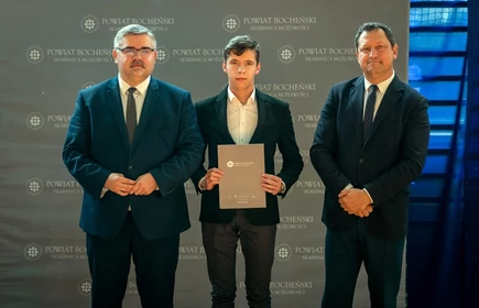 uczeń stojący ze starostą i wicestarostą